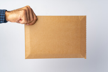 Male hand holding parcel post against white background