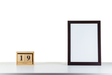 Wooden calendar 32 January with frame for photo on white table and background