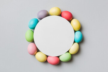 round frame multicolored Easter eggs with white blank paper on a brown background, close-up, space for text, blank for design, selective focus, tinted image