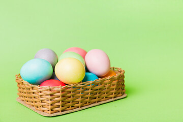 Multi colors Easter eggs in the woven basket on colored background . Pastel color Easter eggs. holiday concept with copy space