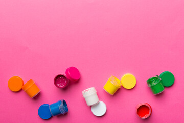 jars with gouache of different colors on Colored background. hobby painting. Top view with empty space. workplace for creativity. home teaching concept drawing