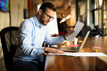 Young businessman using laptop in his office. Handsome man working on the project