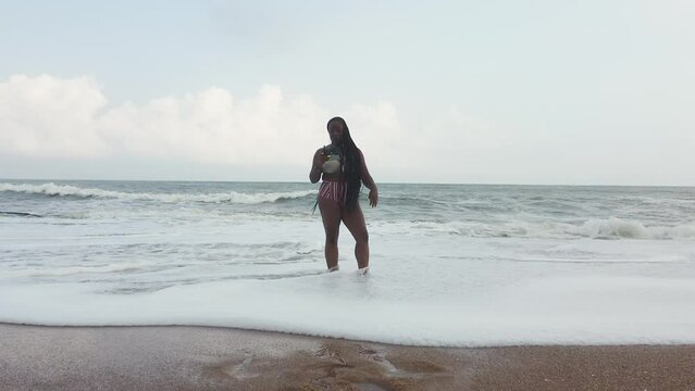 Woman with drone remote control in sea waves, Elmina, Ghana