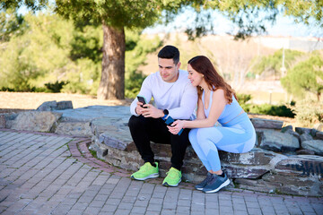 Young couple watching online content on a smartphone sitting in a park