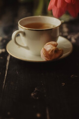 Tee cup on wooden background with spring tulips and white sheet