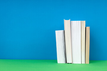 Row of paper books on the green sufrace against blue background.Empty space
