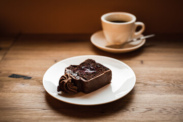 A chocolate cake with cherry filling and a cup of black coffee, selective focus natural light image