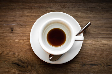 An overhead view of an empty cup of black coffee and a spoon, selective focus natural light image - obrazy, fototapety, plakaty