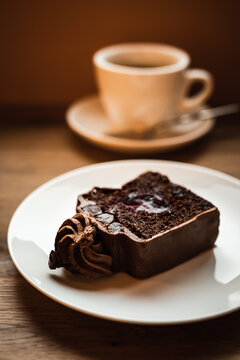 A chocolate cake with cherry filling and a cup of black coffee, selective focus natural light image