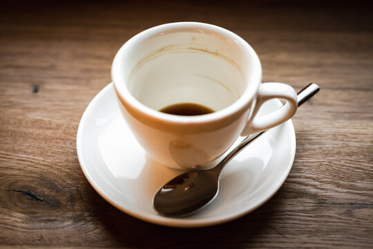 An empty cup of black coffee and a spoon, selective focus natural light image