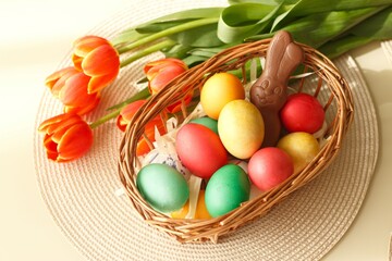 colored eggs and a bunny in a basket next to the flowers.  easter holiday concept.