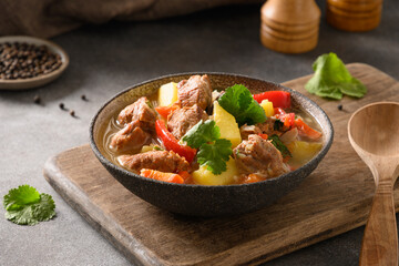 Beef stew with vegetables, potatoes, pepper,carrot in bowl on brown background. Close up.