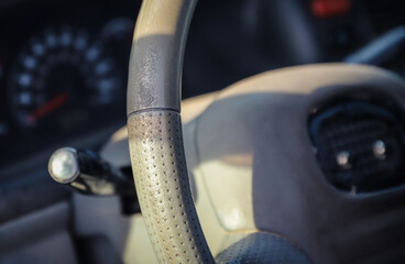 Threadbare automotive gray steering wheel of old auto close-up. Selective focus