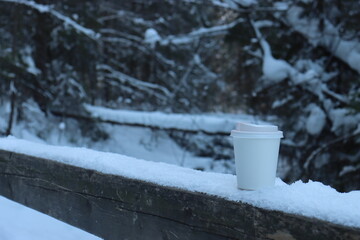 eco-friendly paper cup with a lid among the snow-covered dunes in the Alps. Stands on the railing...