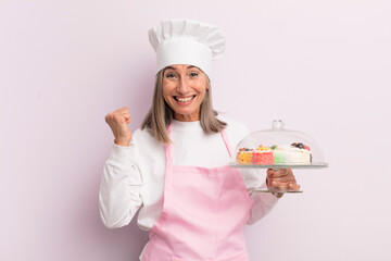 middle age woman feeling shocked,laughing and celebrating success. baker and cakes concept - Powered by Adobe