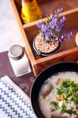 Pork boiled rice with shiitake mushrooms on a black bowl with a spoon on the table.