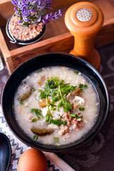 Pork boiled rice with shiitake mushrooms on a black bowl with a spoon on the table.
