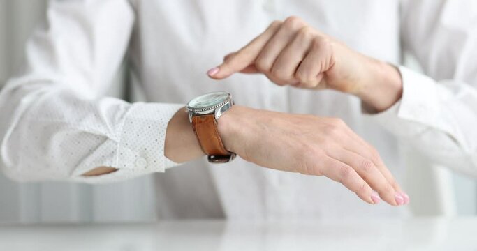 Businesswoman points to wristwatch on hand closeup