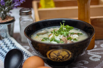 Pork boiled rice with shiitake mushrooms on a black bowl with a spoon on the table.