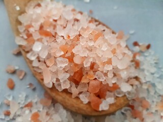 Fototapeta na wymiar Himalayan salt, coarse salt in wooden spoon, selective focus. Thick pink crystals. View from above.