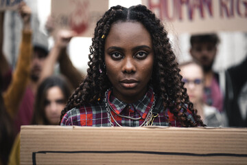 Portrait of a young African woman activist marching during a youth protest - face detail, other...