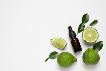 Glass bottle of bergamot essential oil and fresh fruits on white background, flat lay. Space for text - obrazy, fototapety, plakaty