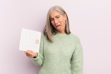 middle age woman feeling disgusted and irritated and tongue out. puzzle challenge concept
