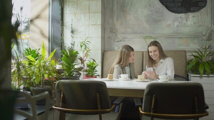 Two girls are sitting at a table in a cafe and solving business issues. Work outside the home