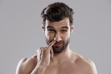 Young dark-haired caucasian man picking in nose