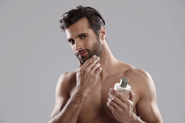 Man holding bottle with perfume and touching beard