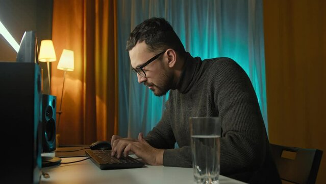 Funny man programmer looking at camera and typing on keyboard