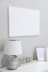 Fototapeta na wymiar Blank canvas on wall over console table with decor indoors. Space for design