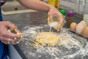 Beautiful young female hands break eggs into flour to knead a beautiful dough.