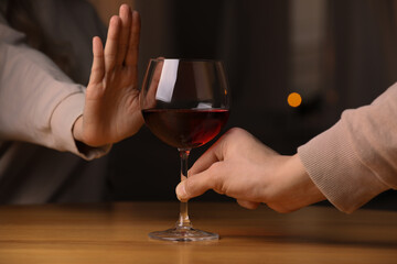 Woman refusing to drink red wine indoors, closeup. Alcohol addiction treatment