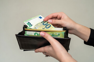 hands of a young stylish luxury girl holding a stylish wallet in which the euro to pay.