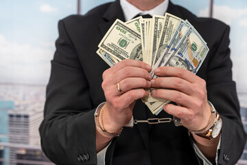 businessman in an expensive black suit ties handcuffs laundering illegal money.