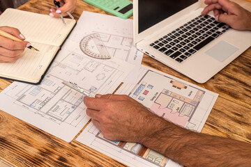  sketches of apartments are considered by workers and work on a laptop on a working day.