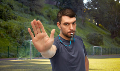 sport, football and people concept - male coach or referee whistling whistle and showing stop...