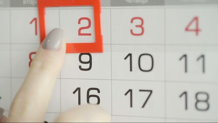 Close-up of a woman's finger moves the date pointer on the calendar
