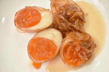 fried egg half cut dressing sweet tamarind sauce topping chop crispy shallot on plate