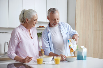 Senior couple having breakfast at home kitchen