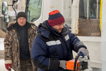 Fototapeta premium Worker cuts ice panel with gasoline saw