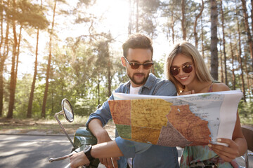 Couple looking USA map on scooter in forest