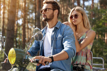 Young caucasian couple riding scooter in forest