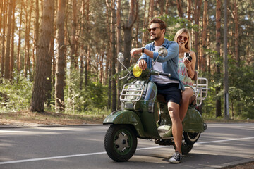 Couple sitting and resting on scooter in forest