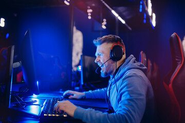 Streamer young man rejoices in victory professional gamer playing online games computer with headphones, neon color © Parilov