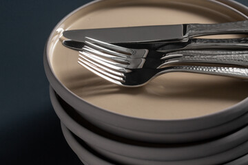 tableware, kitchen utensil and dishes concept - close up of ceramic plates, forks and knives on black table
