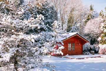Wooden garden shed covered with snow. First snow. Winter in the garden