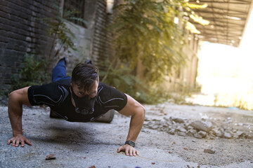 Muscular man wearing sport mask and doing push-ups outdoors.