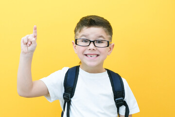 Child boy in glasses isolated on yellow paper wall. Great idea. Happy smiling schoolboy goes back to school. Success, motivation, winner, genius